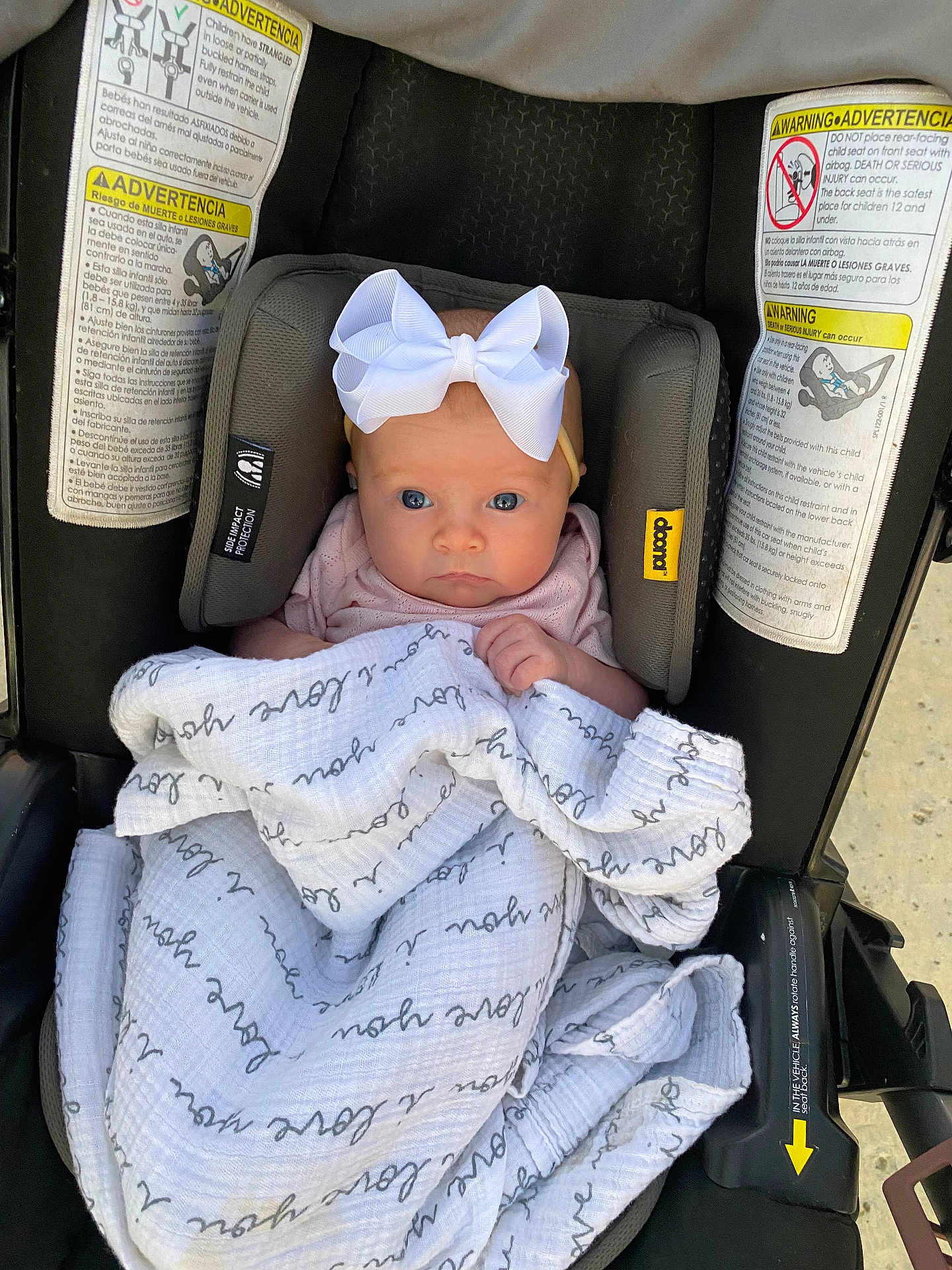 Halston is registered to the contest to win money with this photo: baby, infant, car_seat, blanket, bow, headband, face, person, child, safety, seat, clothing, cute, newborn, wrapped, indoors, warning_labels, soft, pink, expression