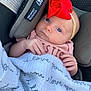 Halston is registered to the contest to win money with this photo: baby, infant, car_seat, red_bow, blanket, blue_eyes, headband, clothing, hand, face, protection, text, closeup, child, sitting, cute, soft, comfort, safety, portrait