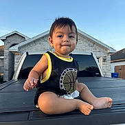 Elias is registered to the contest to win money with this photo: baby, toddler, child, outdoor, truck, vehicle, basketball_tank_top, sky, house, residential, curious, sitting, barefoot, daylight, expression, young_child, portrait, casual_clothing, suburb, smiling