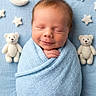 baby, baby_photography, blue_blanket, cozy, crescent_moon, cute, face, indoors, infant, laying_down, newborn, nursery, peaceful, portrait, sleeping, smiling, stars, stuffed_animals, swaddled, teddy_bears
