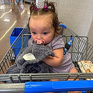 Evelyn joined the competition — help win amazing prizes! toddler, shopping_cart, blanket, pacifier, hair_clips, grocery_store, child, blue_eyes, curly_hair, clothing, person, retail, floor, shopping, aisle, bag, candid, cute, indoor, young_child