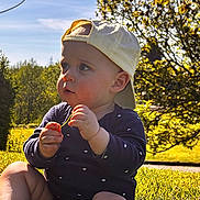 Marius Moreau participe au concours pour gagner de l'argent avec cette photo : baby, child, grass, outdoor, sunlight, hat, yellow_cap, nature, greenery, tree, flower, sitting, cute, daylight, young_child, playing, face, person, casual_clothing, summer