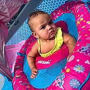 Layla Grace is registered to the contest to win money with this photo: arm, baby, baby_swim, blue, child, cute, head, inflatable_pool, outdoor, patterned, person, pink, pool_float, serious_expression, skin, summer, sunlight, swimsuit, water, yellow