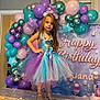 balloons, birthday_party, celebration, child, costume, curtain, decorations, doll, dress, festive, gift_bags, girl, headband, indoor, mermaid, necklace, posing, shoes, smile, table