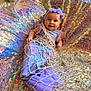 baby, child, smile, face, mermaid_costume, purple, headband, sequin_blanket, net, pillow, indoor, tulle, fabric, cute, lying_down, playful, costume, portrait, colorful, happy