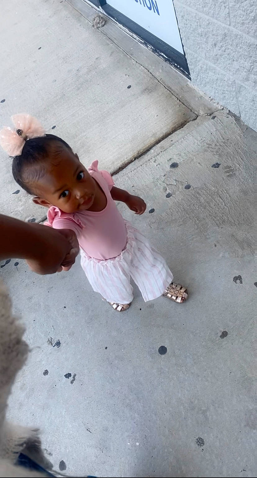 Abigail is registered to the contest to win money with this photo: asphalt, child, city, concrete, flooring, foot, fun, happy, human_leg, leg, leisure, person, play, recreation, road, road_surface, sand, sidewalk, sitting, soil