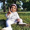 toddler, child, grass, park, trees, sunlight, outdoor, pink_bonnet, white_cardigan, striped_dress, white_leggings, white_shoes, stick, pacifier, smiling, sitting, nature, daylight, cute, face