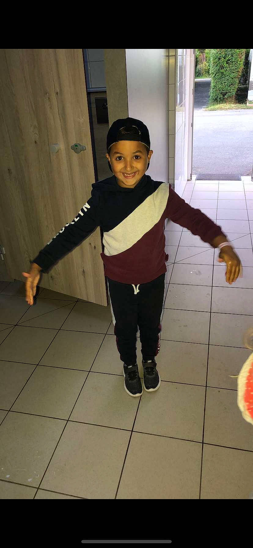 Yanis participe au concours pour gagner de l'argent avec cette photo : child, costume, door, fashion_design, floor, flooring, fun, happy, hat, headwear, joy, leg, person, personal_protective_equipment, play, sleeve, smile, snapshot, sneakers, sweatpant