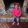 Jaliyah is registered to the contest to win money with this photo: accessories, casual_clothing, child, cozy, fireplace, girl, happy, home, indoor, person, pink_bow, pink_sweatshirt, portrait, ripped_jeans, rustic, seated, smiling, sneakers, stone_hearth, wooden_floor