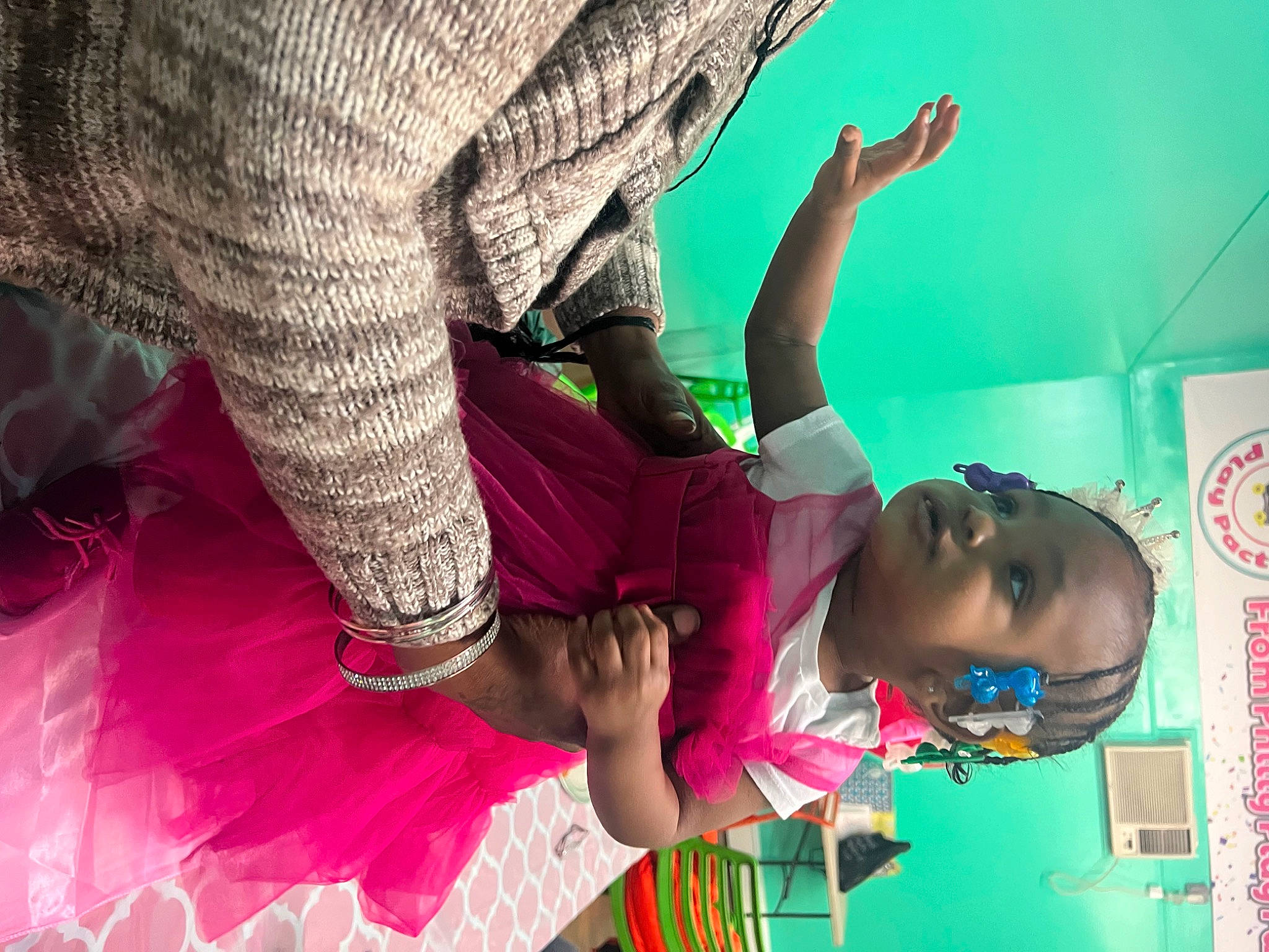 Naomi is registered to the contest to win money with this photo: arm, child, event, foot, fun, green, happy, human, human_leg, leisure, magenta, pattern, person, pink, play, purple, room, textile, thigh, toddler