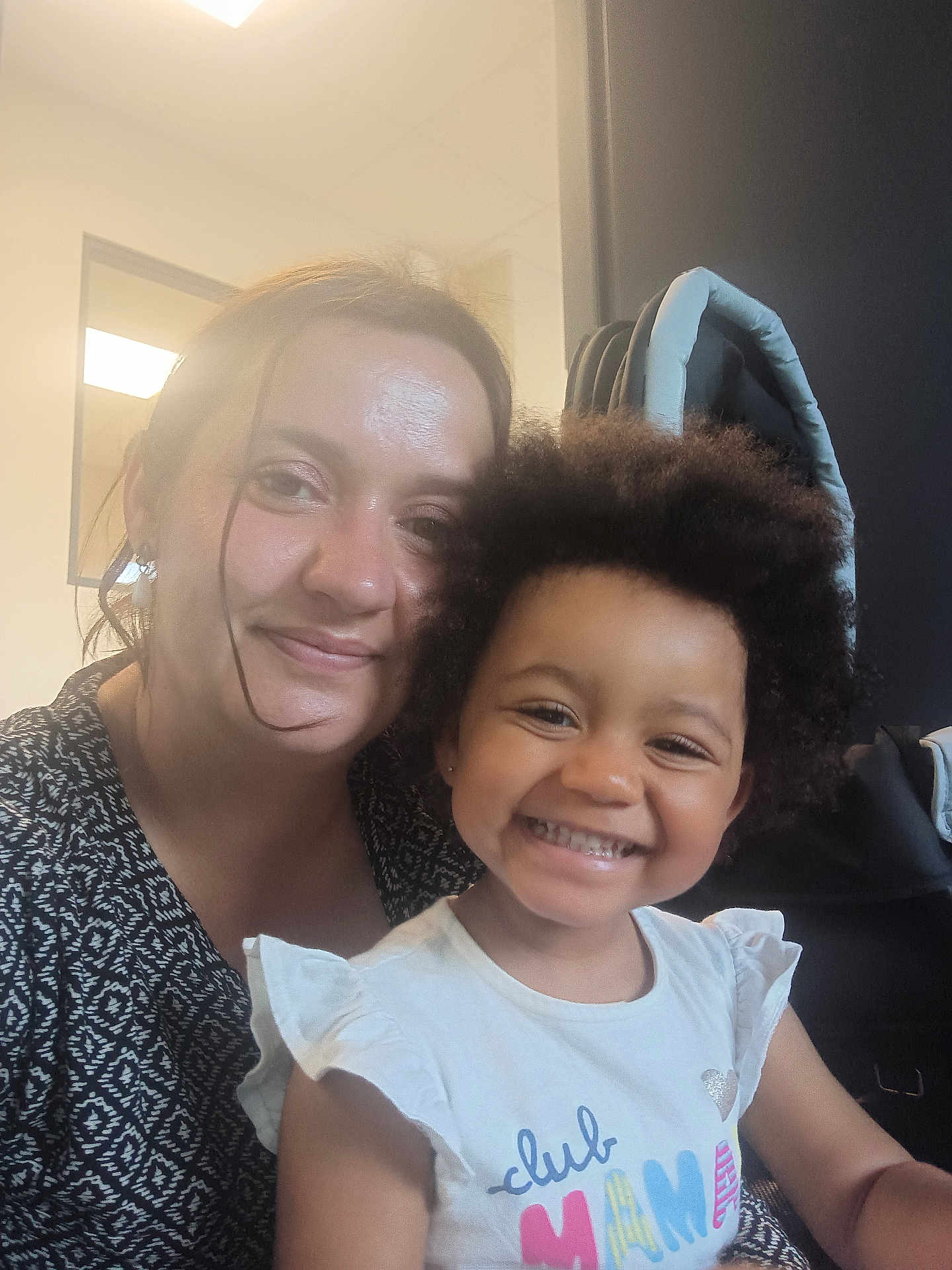 Adr participe au concours pour gagner de l'argent avec cette photo : child, woman, smile, happy, indoor, portrait, afro_hair, casual_clothing, white_shirt, black_and_white_pattern, face, female, toddler, person, hair, closeup, seated, light, window, furniture
