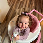 Jourdyn joined the competition — help win amazing prizes! baby, baby_walker, bow, child, clothing, cute, feeding, hair_accessory, happy, holding, indoor, infant, milk_bottle, person, pink, portrait, sitting, smiling, white, wooden_floor