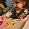 baby_clothes, cereal, child, curiosity, curly_hair, cute, expression, face, feeding, food, hand, high_chair, indoor, light, room, seat_belt, table, toddler, window, young_child