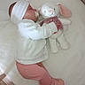 baby, infant, sleeping, pacifier, headband, stuffed_toy, bunny, crib, blanket, pink_clothing, white_clothing, soft_toy, child, indoor, cozy, cute, peaceful, toddler, footwear, toy