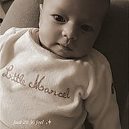 Ezya participe au concours pour gagner de l'argent avec cette photo : baby, infant, child, face, portrait, clothing, sitting, indoor, cute, expression, looking, young, cozy, text_overlay, sepia, soft_light, human, people, sleepwear, embroidered
