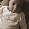 baby, infant, child, face, portrait, clothing, sitting, indoor, cute, expression, looking, young, cozy, text_overlay, sepia, soft_light, human, people, sleepwear, embroidered
