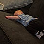 baby, infant, couch, sofa, clothing, blue_shirt, black_pants, socks, relaxing, indoor, furniture, pillow, home, child, person, lying_down, cute, small, resting, cozy