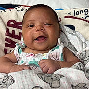 Amarah is registered to the contest to win money with this photo: baby, smiling, blanket, elephant_pattern, infant, happy, bed, pillow, clothing, cute, child, face, portrait, indoors, cozy, comfort, young, skin, hands, lying_down