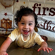 Naim joined the competition — help win amazing prizes! baby, child, smiling, crawling, curly_hair, birthday, balloons, presents, floor, wooden_floor, tshirt, happy, indoors, celebration, face, person, young_child, excited, background, decorations