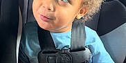 Noah is registered to the contest to win money with this photo: blue_shirt, car_interior, car_seat, casual_clothing, child, curly_hair, cute, indoors, looking_up, person, playful_expression, portrait, safety_harness, seat, seatbelt, sitting, toddler, vehicle, young_child, young_person