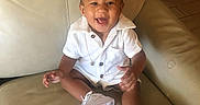 Zion is registered to the contest to win money with this photo: accessory, baby, casual, child, cute, fashion, happy, indoor, infant, joyful, leather_chair, one_person, person, portrait, seated, sitting, smile, sneakers, white_clothing, young_child