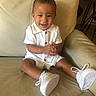 Zion is registered to the contest to win money with this photo: baby, casual_clothes, child, clapping, couch, cute, furniture, happy, home, indoors, joyful, living_room, person, short_hair, sitting, small_shoes, smiling, white_outfit, white_shoes, young_child