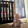 baby, child, pajamas, carpet, crib, stuffed_animals, firetruck, curtain, natural_light, indoor, floor, toy, furniture, cute, infant, person, clothing, home, room, sitting
