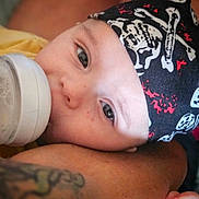 Mariùs a rejoint le concours — aidez-le/la à gagner de superbes lots ! arm, baby, bandana, bottle, casual, child, closeup, cute, face, feeding, headwear, indoor, infant, person, pirate, portrait, resting, skin, tattoo, young