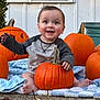 baby, pumpkin, jack_o_lantern, blanket, outdoor, smiling, happy, fall, autumn, holiday, cute, child, nature, plant, orange, feet, grass, face, clothing, sitting