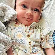 Zachary joined the competition — help win amazing prizes! baby, infant, blanket, onesie, patterned_clothing, smile, face, hand, skin, eyes, head, cute, soft_texture, portrait, indoors, cozy, closeup, child, newborn, person
