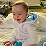 baby, child, toy, hoodie, blanket, bed, indoor, happy, smiling, playing, infant, person, soft, warm, cozy, colorful, cute, young, candid, casual