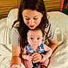 Zachary joined the competition — help win amazing prizes! woman, baby, bed, phone, smile, indoor, holding, clothing, socks, face, person, portrait, looking_down, wooden_headboard, blanket, cute, expression, casual, family, moment