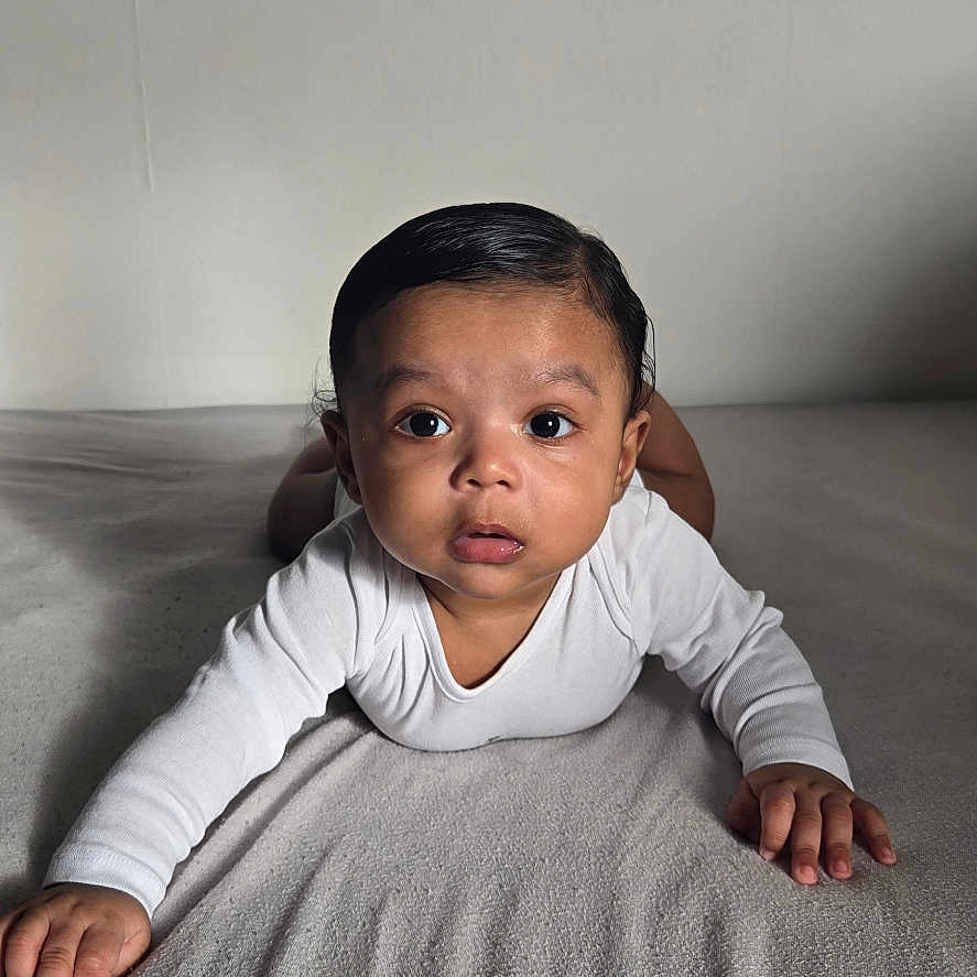 Théo participe au concours pour gagner de l'argent avec cette photo : baby, child, infant, tummy, blanket, white_clothing, curious, lying_down, indoor, portrait, face, expression, young, person, soft_texture, neutral_background, small_hands, cute, looking_at_camera, one_person