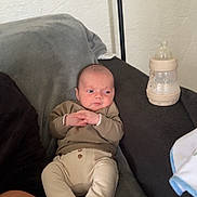 Lyam participe au concours pour gagner de l'argent avec cette photo : baby, infant, couch, blanket, bottle, clothing, socks, footwear, person, indoors, relaxing, seated, expression, wall, texture, baby_bottle, soft_fabric, casual, home, cute