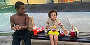 Bleu Enzo Caban joined the competition — help win amazing prizes! child, children, bench, drink, food, hot_dog, sneakers, shorts, sweater, shirtless, sidewalk, window, reflection, urban, street, snack, happy, smile, outdoor, person