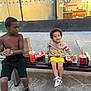 child, children, bench, drink, food, hot_dog, sneakers, shorts, sweater, shirtless, sidewalk, window, reflection, urban, street, snack, happy, smile, outdoor, person