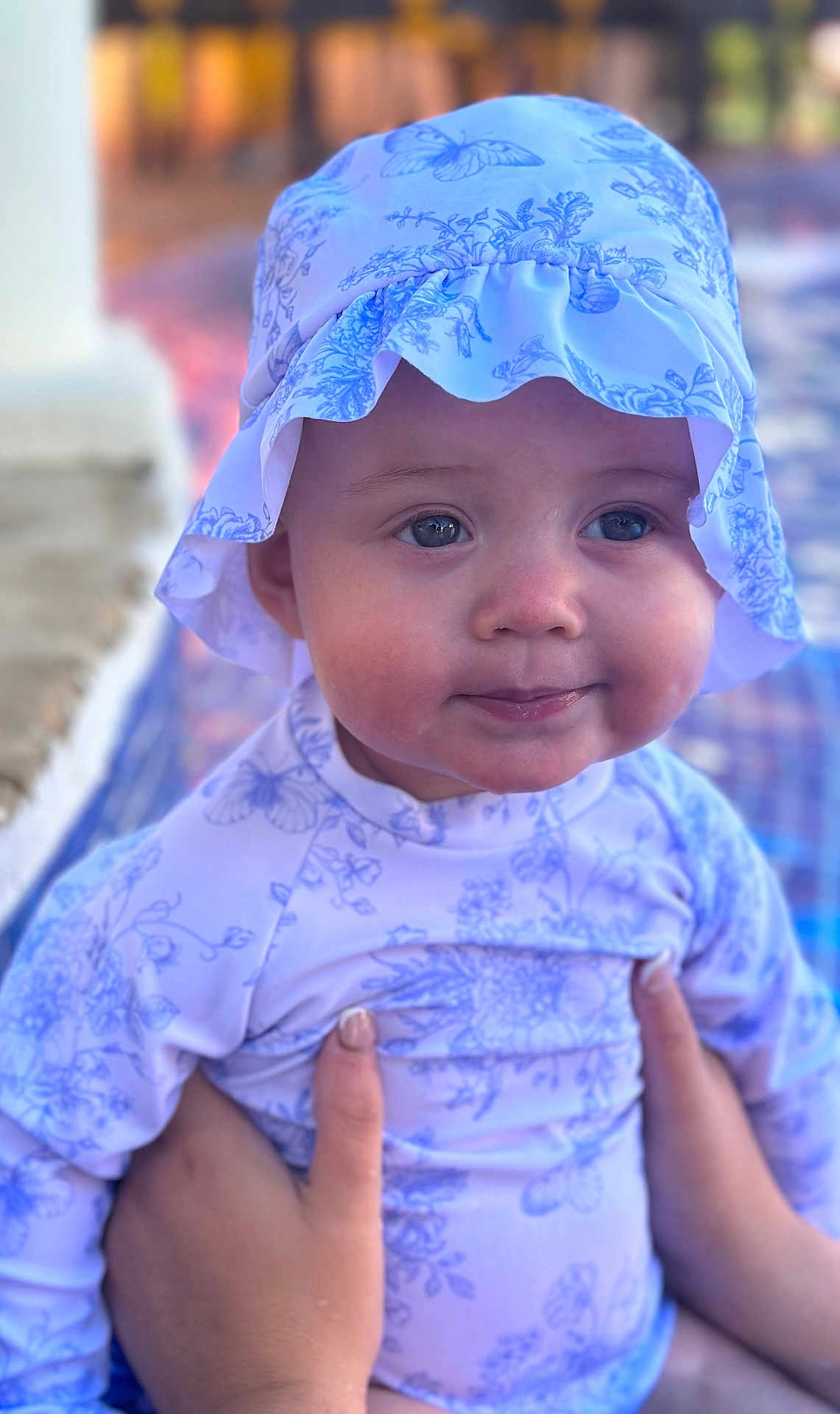 Remi joined the competition — help win amazing prizes! baby, child, infant, hat, sun_hat, floral_pattern, clothing, hands, holding, portrait, cute, face, blue_eyes, outdoor, soft_focus, skin, expression, person, smile, young