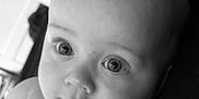Remi is registered to the contest to win money with this photo: baby, infant, face, close_up, black_and_white, eyes, skin, portrait, child, cute, expression, young, head, person, human, soft, innocence, newborn, looking, curious