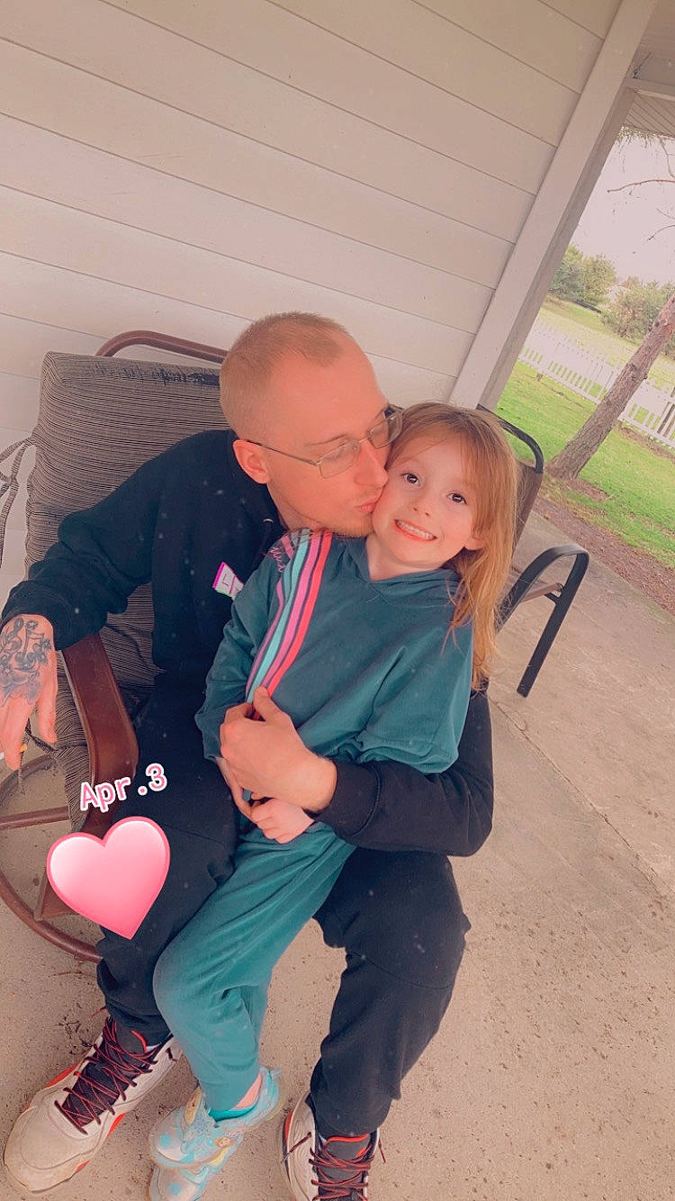 Alyssa is registered to the contest to win money with this photo: child, event, eyewear, fun, glasses, happy, human_leg, interaction, joy, kiss, knee, lap, leisure, mouth, person, plant, shoe, sitting, sneakers, thigh