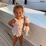 Alma participe au concours pour gagner de l'argent avec cette photo : barefoot, boat, bunny, child, cute, girl, hair_bun, happy, nautical, outdoor, playful, smiling, stuffed_animal, summer, sunlight, sunset, swimsuit, toy, vacation, wooden_deck