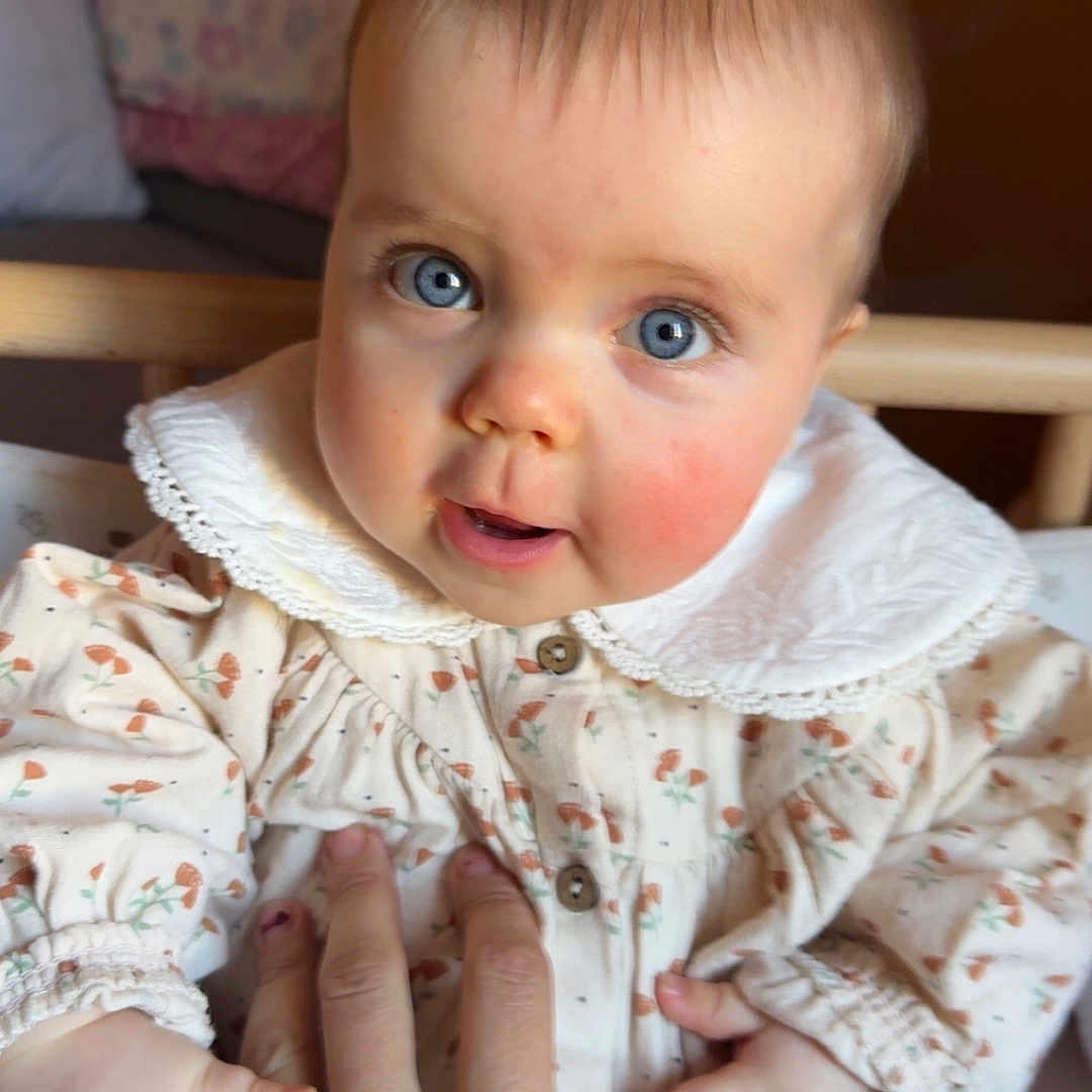 Lola participe au concours pour gagner de l'argent avec cette photo : accessories, baby, bodypart, clothing, coat, couch, face, finger, furniture, hand, happy, head, knitwear, newborn, person, photography, portrait, sitting, smile, sweater