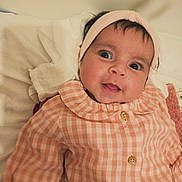 Nina participe au concours pour gagner de l'argent avec cette photo : baby, infant, headband, clothing, orange_checkered, buttoned_shirt, blanket, soft_fabric, face, eyes, smile, indoor, portrait, cute, child, newborn, person, lying_down, cozy, expression