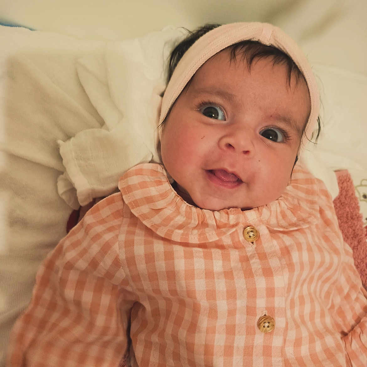 Nina participe au concours pour gagner de l'argent avec cette photo : baby, infant, headband, clothing, orange_checkered, buttoned_shirt, blanket, soft_fabric, face, eyes, smile, indoor, portrait, cute, child, newborn, person, lying_down, cozy, expression