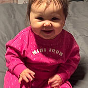 Zoey joined the competition — help win amazing prizes! baby, child, smiling, pink_clothing, sitting, indoors, happy, face, person, cute, young_child, pajamas, hair_tied, cozy, soft_lighting, portrait, infant, small_hands, casual, home