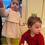 Cylia participe au concours pour gagner de l'argent avec cette photo : child, toddler, indoor, window, dress, sweater, blanket, curly_hair, earrings, yellow_floor, wall_outlet, standing, sitting, cute, person, portrait, fuzzy_clothing, curious, baby, two_children