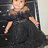 toddler, child, dress, black_dress, hair_accessory, indoor, carpet, dresser, furniture, smile, pose, person, cute, fashion, footwear, bow, expression, young_child, portrait, standing
