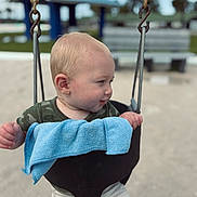 Carter joined the competition — help win amazing prizes! baby, swing, playground, child, outdoor, blond_hair, blue_towel, shorts, green_shirt, sand, metal_chains, seat, park, summer, daylight, curious, infant, cute, seat_swing, fun