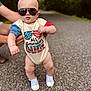 baby, toddler, sunglasses, onesie, shoes, road, outdoor, person, child, holding_hands, summer, casual_clothing, cute, walking, american_flag, fashion, portrait, fun, expression, legs