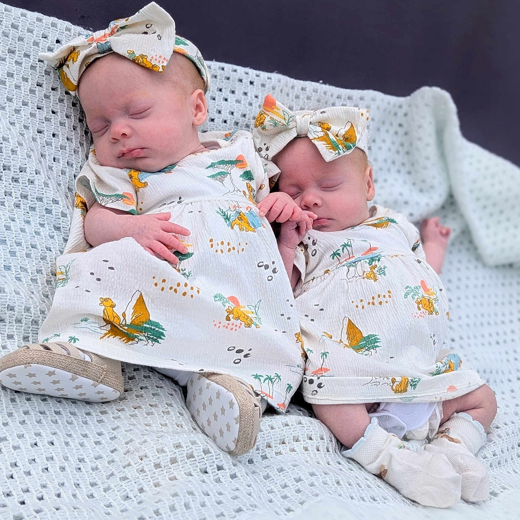 Luna And Lyla is registered to the contest to win money with this photo: adorable, baby, blanket, clothing, cute, footwear, hand_holding, headband, indoor, infant, matching_outfits, newborn, patterned_dress, peaceful, portrait, sleeping, socks, soft_texture, twin, white