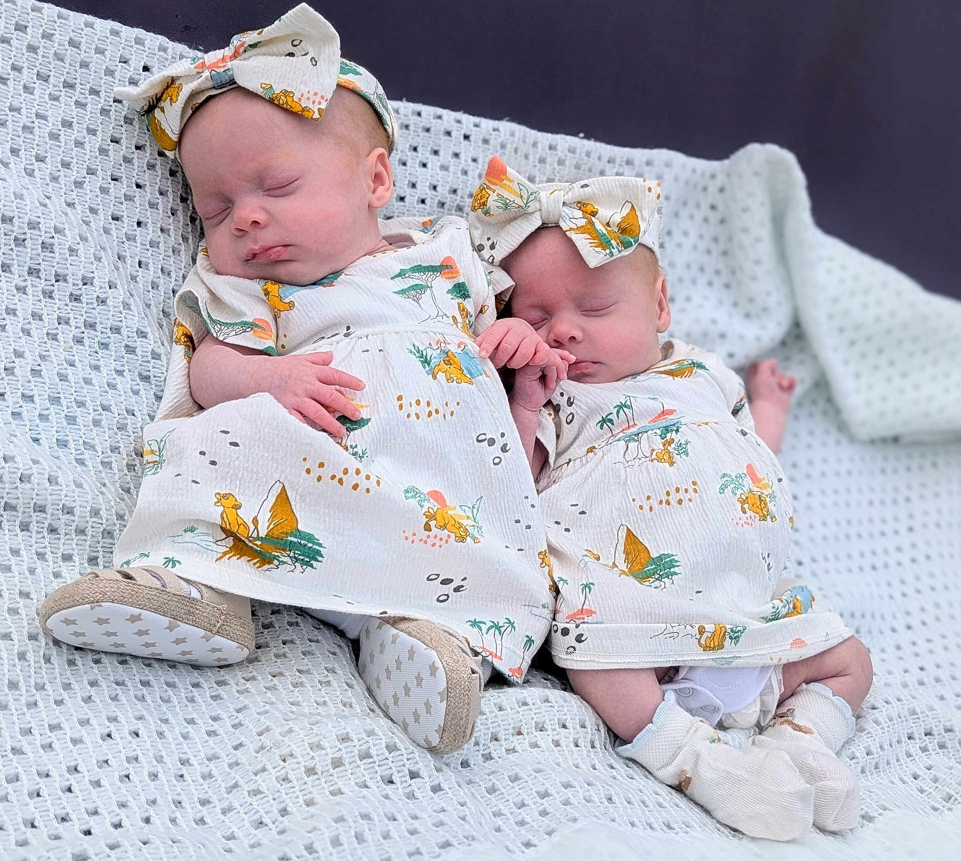 Luna And Lyla is registered to the contest to win money with this photo: adorable, baby, blanket, clothing, cute, footwear, hand_holding, headband, indoor, infant, matching_outfits, newborn, patterned_dress, peaceful, portrait, sleeping, socks, soft_texture, twin, white